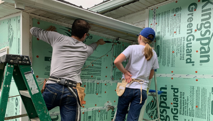 Youth on ASP mission trip work on siding for a house 